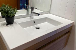 a white sink in a bathroom with a potted plant at The Swiss Chalet Apartment 9 - Seaview - Top Floor - Air Conditioning & Wi-Fi - Bay of Islands in Paihia