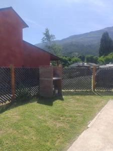 een hek naast een rood gebouw met een bank bij Departamentos Mate de Luna in El Bolsón