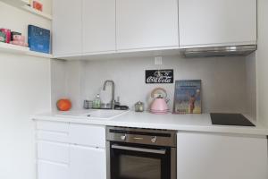 een keuken met witte kasten, een wastafel en een fornuis bij 31 m fully renovated love nest in Boulogne-Billancourt