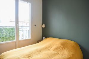 een bed in een slaapkamer met een groot raam bij 31 m fully renovated love nest in Boulogne-Billancourt