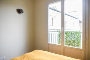 een slaapkamer met een bed en een groot raam bij 31 m fully renovated love nest in Boulogne-Billancourt