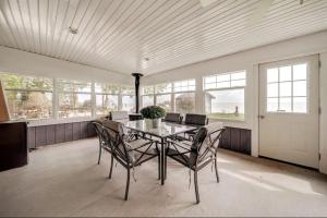 a dining room with a table and chairs and windows at Lakeshore Bliss Retreat in Wheatley