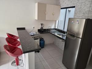 a kitchen with a stainless steel refrigerator and a red stool at Ingá Hospedagem in Porto Velho
