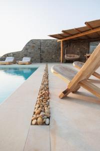a pool with a row of rocks next to a swimming pool at Birdhouse Private Luxury Suite in Agios Ioannis Mykonos