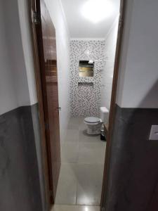 een badkamer met een toilet en een deur naar een kamer bij Casa Térrea c/ Piscina - 100mts praia in Caraguatatuba