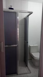 a bathroom with a toilet and a glass shower door at Quarto Disponível em Sobrado in Sao Paulo