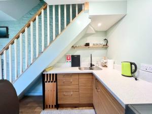 a kitchen with a sink and a staircase at Little Oasis with Sea Views in Stoke Fleming