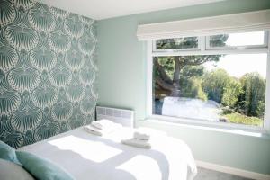 a bedroom with a white bed and a window at Little Oasis with Sea Views in Stoke Fleming