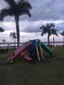 a playground with a slide and palm trees on the beach at L207 Apartamento em resort à beira lago in Brasília