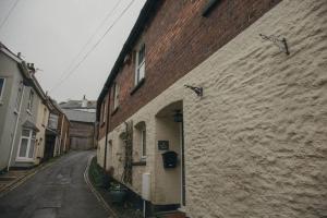 an alley with a brick building with clocks on it at Beautifully decorated bright and cosy cottage in Aveton Gifford