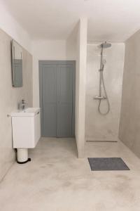 La salle de bains blanche est pourvue d'un lavabo et d'une douche. dans l'établissement Villa Floresco, à Nerezine