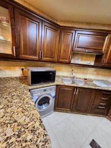 cocina con lavadora y microondas en Dair Ghbar - Amman Apartment, en Amán