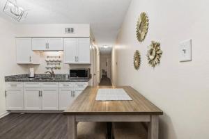 cocina con armarios blancos y mesa de madera en Glamorous @Midtown W/ King suite, en Memphis