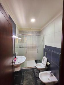 a bathroom with two sinks and a shower and a toilet at Dair Ghbar - Amman Apartment in Amman