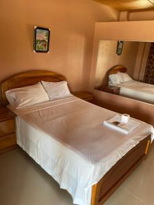 1 dormitorio con 2 camas con sábanas blancas en HOSTAL LOS NOGALES, en Aguaytía