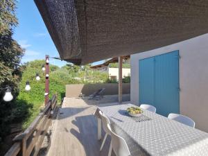 una mesa con sillas y una puerta azul en un patio en Maisonnette avec 2 chambres climatisée en face de la plage de Gigaro, en La Croix-Valmer