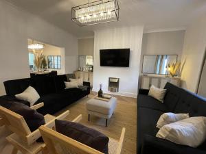uma sala de estar com sofás pretos e uma televisão em Château by the Sea - Luxury hotel style 3 bed with hot tub em Newbiggin-by-the-Sea