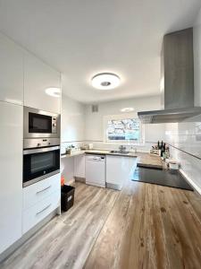 uma grande cozinha com electrodomésticos brancos e pisos em madeira em Casa Begur vistas espectaculares em Begur