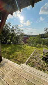una terraza de madera con un banco en un campo en Sentral og romslig leilighet nært Senja, en Finnsnes