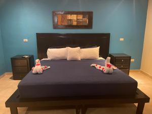 dos animales de peluche están sentados en una cama en Hotel Brisa, en Punta Cana