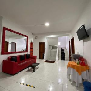 a living room with a red couch and a tv at Hotel La Mansión del Sol in Tuluá