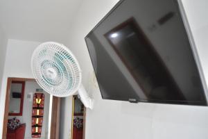 a flat screen tv attached to a wall with a fan at Hotel La Mansión del Sol in Tuluá