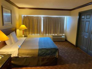Dominion Inn and Suites في ساندستون: غرفة فندقية بسرير كبير ونافذة