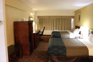 Dominion Inn and Suites في ساندستون: غرفة فندقية بسريرين ومكتب