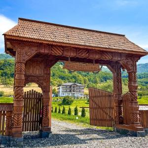 a wooden pavilion with a house in the background at Pensiunea Hanul Morosenilor in Onceşti