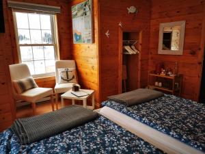 um quarto com uma cama, uma cadeira e uma janela em L'Ancrage B&B and Cottages em Saint Louis de Kent