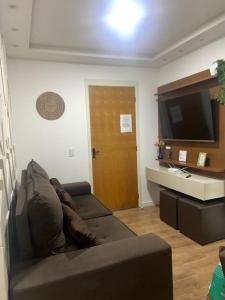 uma sala de estar com um sofá e uma televisão de ecrã plano em Apartamento 2 Quartos c/ Vaga de Estacionamento em Serra