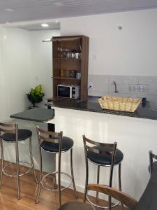 a kitchen with four bar stools and a counter at RCM Vilas - Studio 103 Deluxe in Joinville