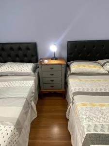 a room with two beds and a table with a lamp at RCM Vilas - Studio 103 Deluxe in Joinville