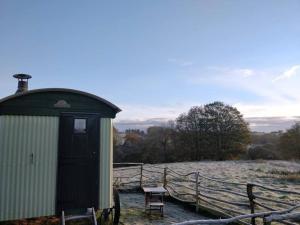 ein kleiner Schuppen mit einer Bank neben einem schneebedeckten Feld in der Unterkunft Cefnmachllys Shepherds Huts in Brecon