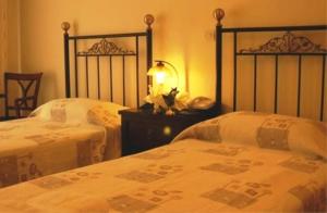 a bedroom with two beds and a table with a lamp at Aegeon Hotel in Karlovasi
