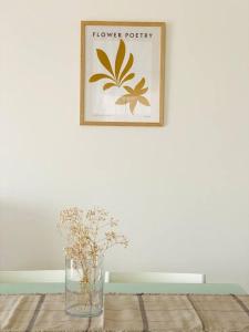 Groovy Apartment في تريبوليس: مزهرية مع الزهور على طاولة مع صورة