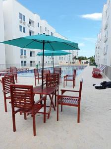 a table and chairs with an umbrella next to a pool at Apto cerca al mar amoblado. in Coveñas