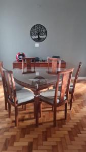 a dining room table with four chairs and a tree clock at Pousada Central in Bragança Paulista