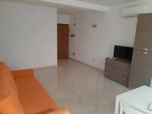 een woonkamer met een oranje bank en een televisie bij Estrela do Mar in Santa Maria