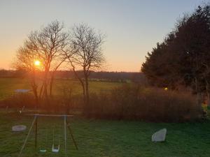 une balançoire dans un champ avec le coucher du soleil en arrière-plan dans l'établissement Plume - Dormir Comme A La Maison, à Guérande