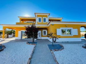 una casa amarilla con un camino delante de ella en Villa Malia Algarve, en Mexilhoeira Grande
