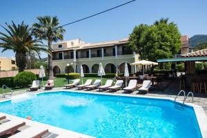 a swimming pool with chairs and a building at Tereza Apartments in Acharavi