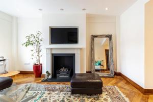 een woonkamer met een spiegel en een open haard bij Colourful South Kensington Home in Londen