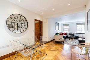 sala de estar con mesa de cristal y sillas en Colourful South Kensington Home, en Londres