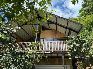 a house with a balcony in the middle of trees at Bonita cabaña estilo glamping in Juayúa