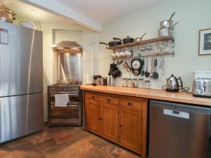 a kitchen with a stainless steel refrigerator and wooden cabinets at 6 The Whinlands in Leiston