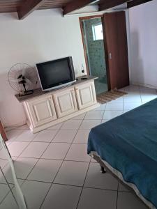 1 dormitorio con TV de pantalla plana y ventilador en Casa da Praia em Costazul en Rio das Ostras