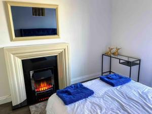a bedroom with a fireplace and two blue pillows on a bed at Stanley Place in Na Clocha Liatha