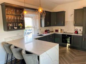 a kitchen with a large white counter and chairs at Stanley Place in Greystones