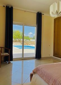 1 dormitorio con cama y vistas a la piscina en Villa Malia Algarve, en Mexilhoeira Grande